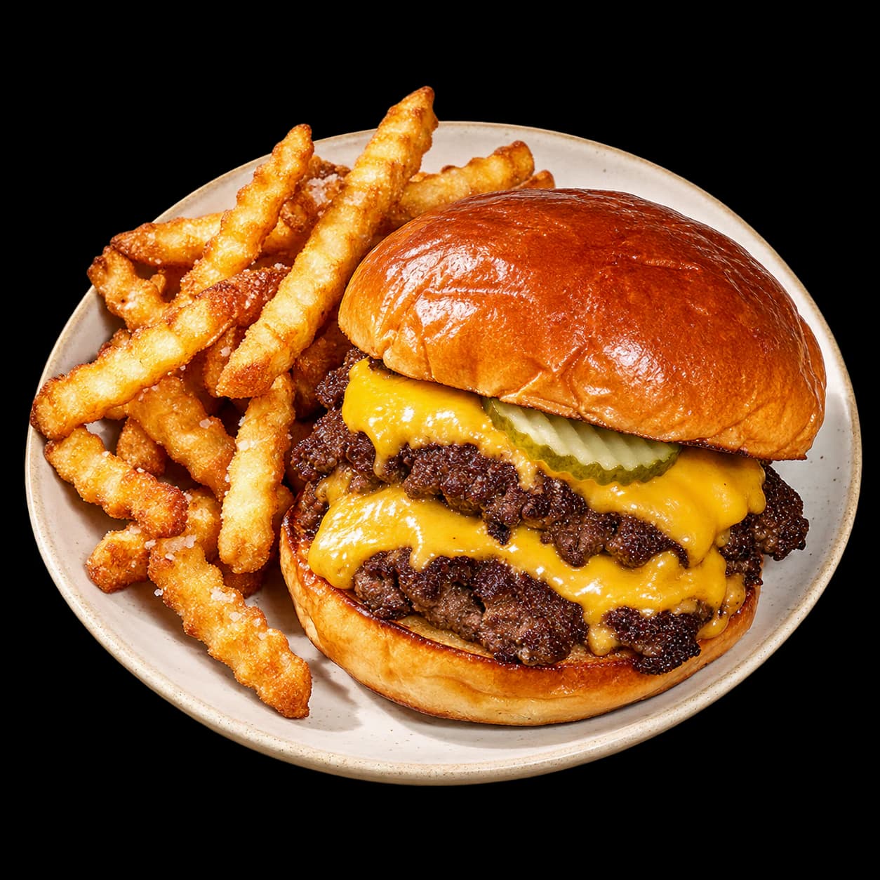 Burger with cheese and pickles beside crisp fries